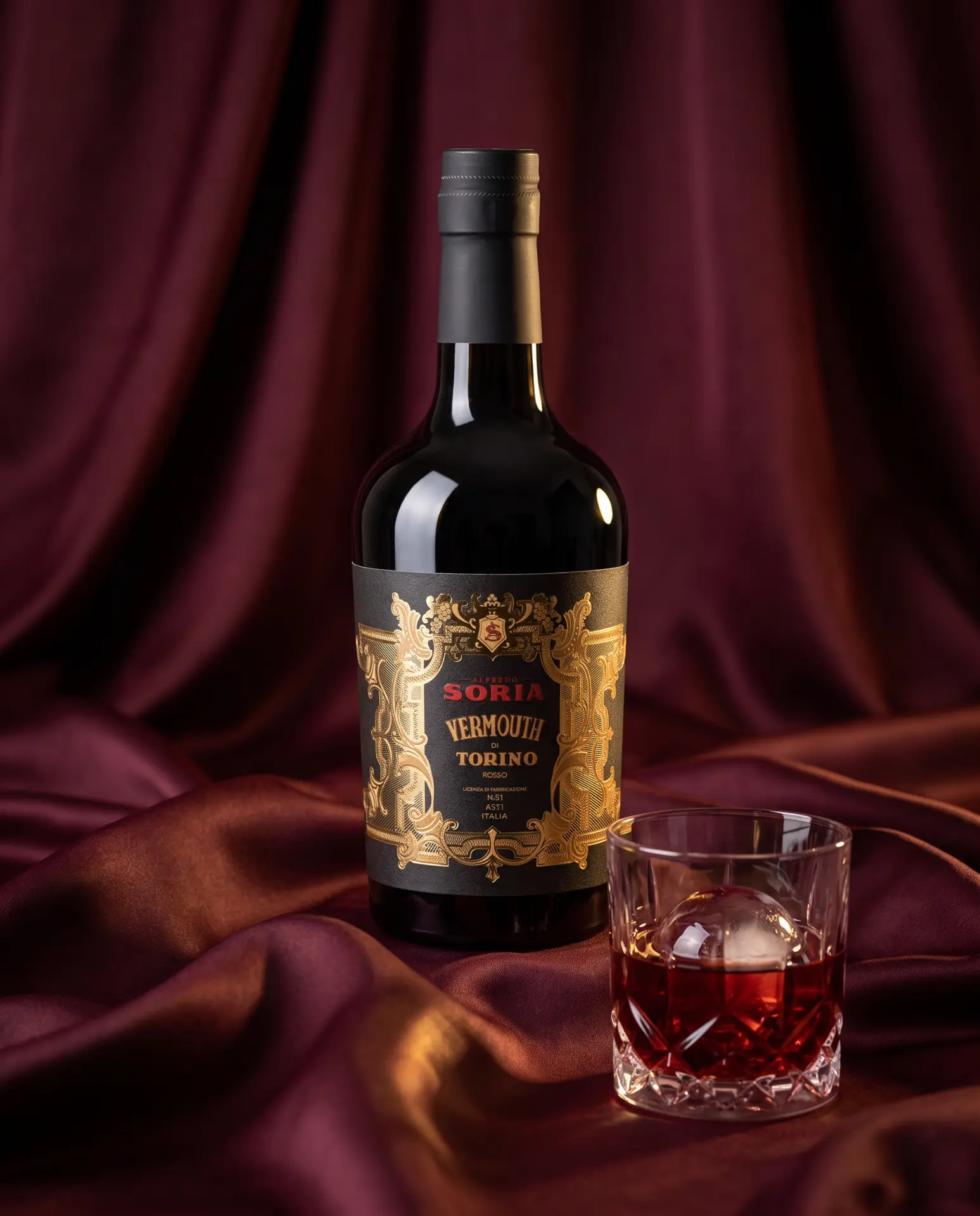 Alfredo Soria Vermouth di Torino bottle on burgundy silk with a rocks glass